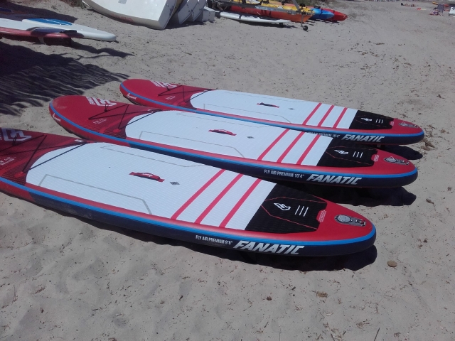  Tres tablas de Stand Up Paddle colocadas en la arena 