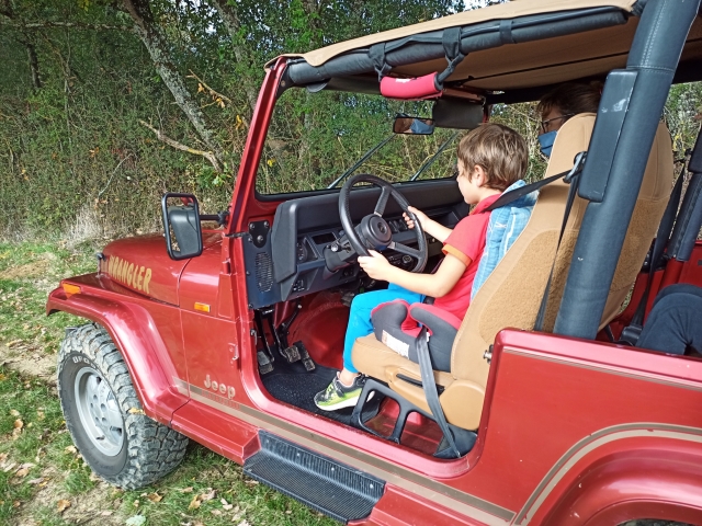 Niño al volanle de un jeep con la guía del instructor