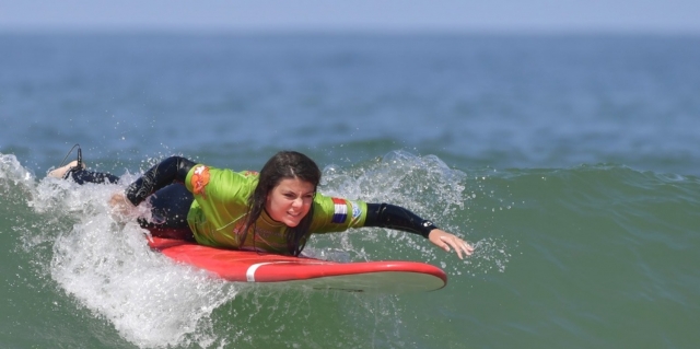 Estudianle de surf nadando sobre la ola