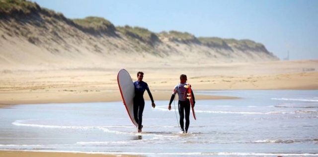 Dos surfistas paseando por la playa