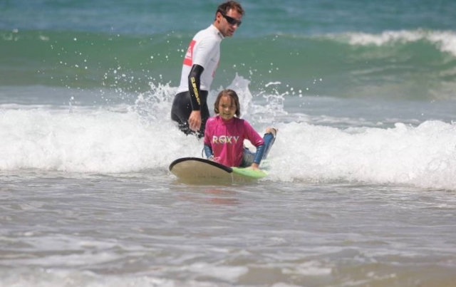  ¡Un instructor que se acerca a un pequeño surfista! 