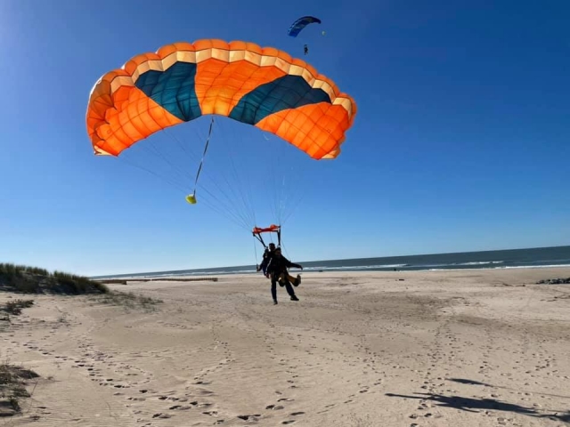 Aterrizaje en paracaídas en la playa después del salto tándem 